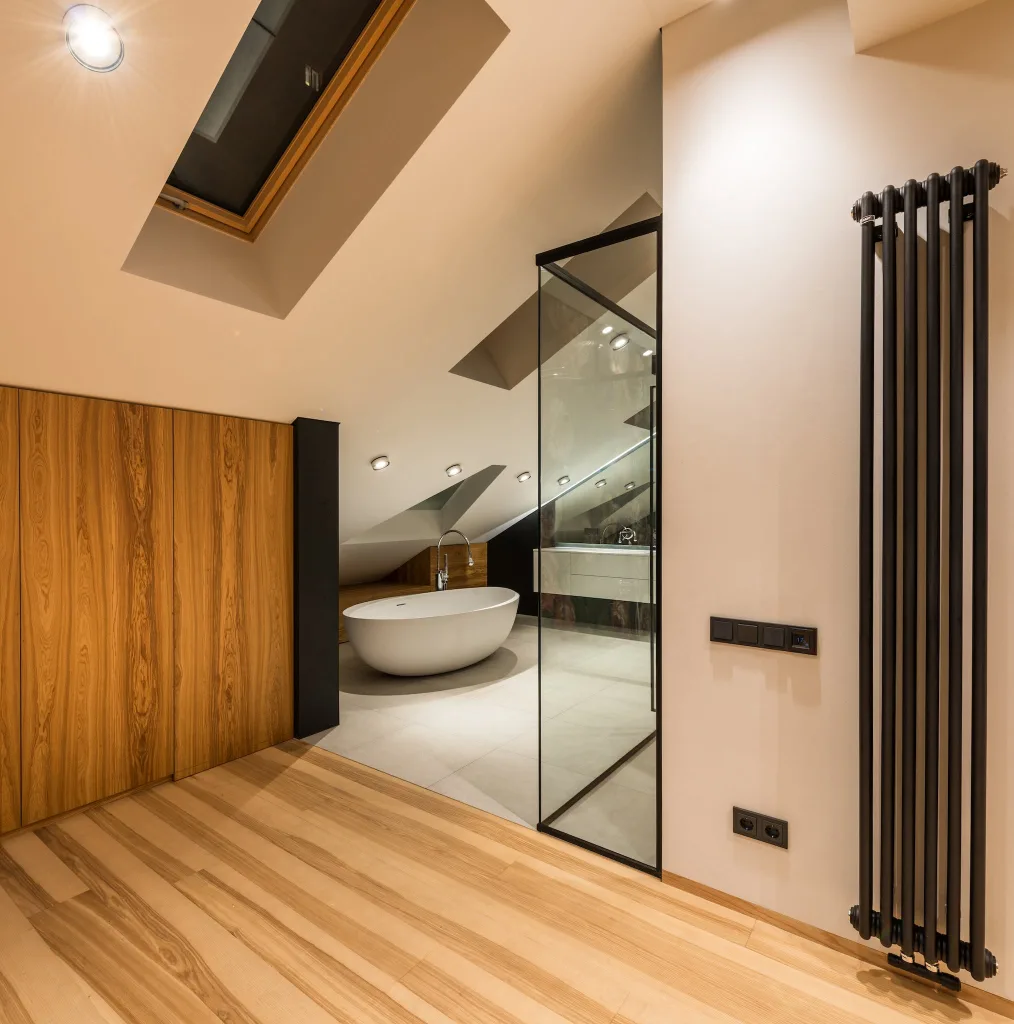 Interior of modern bathroom with wooden elements near entrance and bright illumination over bathtub