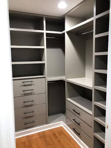 A small corner closet setup with gray shelving units and multiple drawers for organized storage.