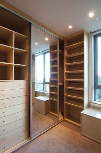 A narrow closet space featuring mirrored sliding doors and built-in shelves with a city view.