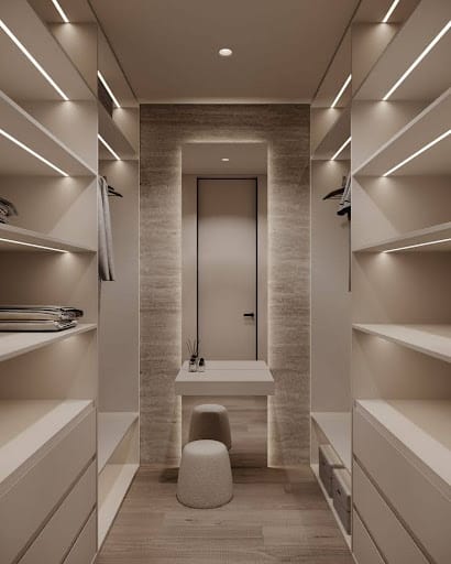 A compact walk-in closet with sleek beige tones, modern lighting, and a built-in vanity area.
