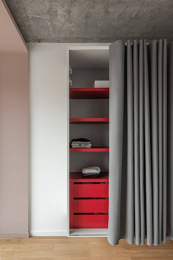 A chic storage nook hidden behind a gray curtain in a modern apartment.
