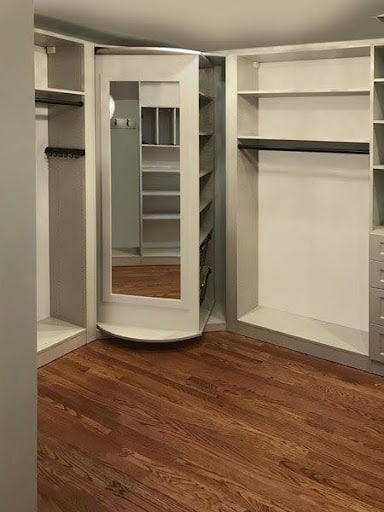 A curved corner mirror reflecting a small, efficiently organized closet space.
