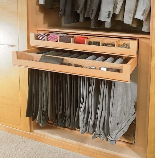 A detailed view of a pull-out trouser rack in a light wood-toned built-in wardrobe.