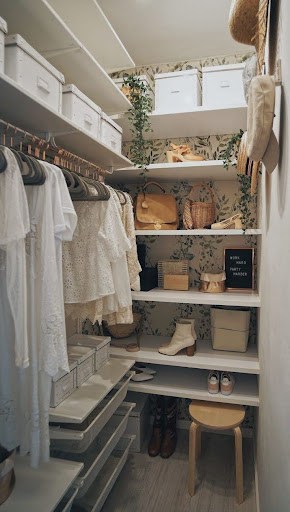 A quaint, bohemian-style clothes closet with open shelving and wicker baskets.
