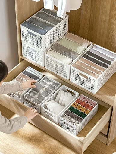 A practical drawer organizer containing neatly sorted accessories in a wooden closet system.
