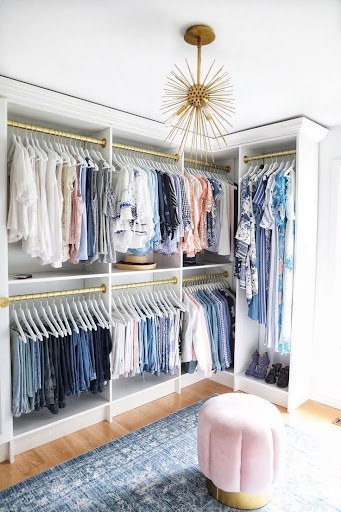 A chic Free Standing Closet featuring gold accents, pastel seating, and organized racks for a soft, fashionable touch.