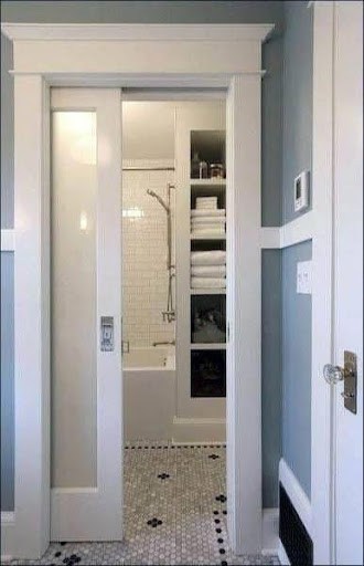 This slim Pocket Door or Sliding Door entrance reveals a snug shower space with pristine white subway wall tiles, accented by a black and white mosaic tile flooring that gives a classic touch to the compact bathroom.
