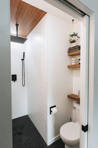 Cozy Compact Fixtures small bathroom shower with wooden accents, white subway tiles, and black hardware, exuding rustic charm.
