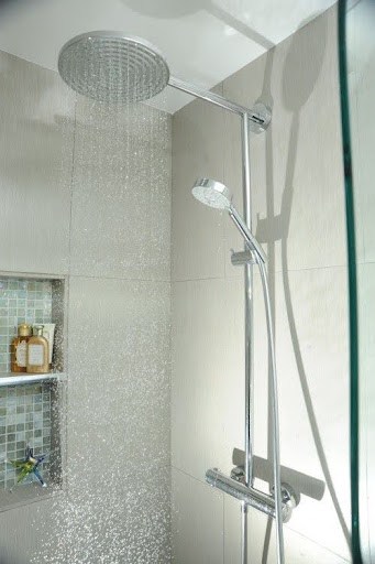 Small bathroom shower with dual showerheads and a niche for products, highlighting a rainfall shower experience.