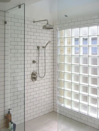 Compact but bright bathroom shower area with white subway tiles and glass block partition, creating an inviting, light-filled space.