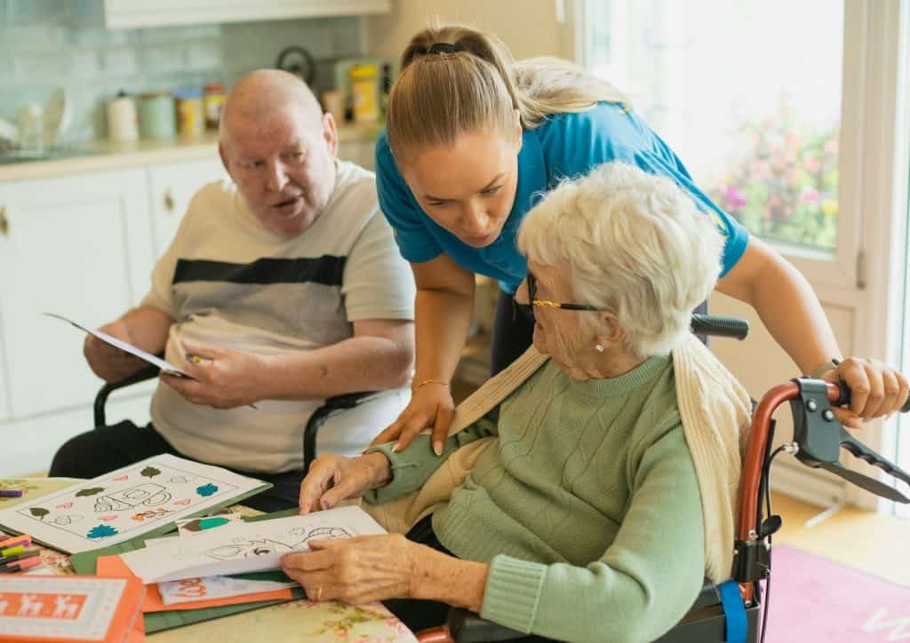 UNDERSTANDING HOPA: RULES FOR 55+ HOUSING COMMUNITIES 8 Caregiver assisting elderly couple with coloring