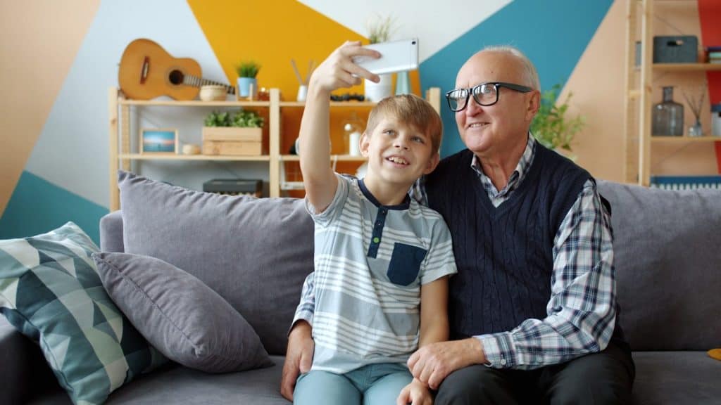 UNDERSTANDING HOPA: RULES FOR 55+ HOUSING COMMUNITIES 7 Grandfather and grandson taking a selfie on the couch.